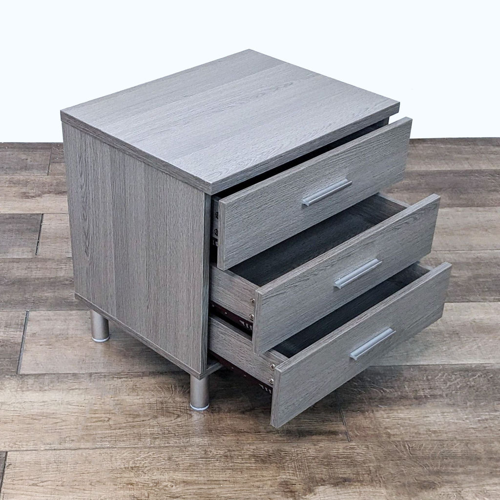 2. Opened drawers of a grey end table revealing internal storage on a wooden floor, by Ana Furniture.
