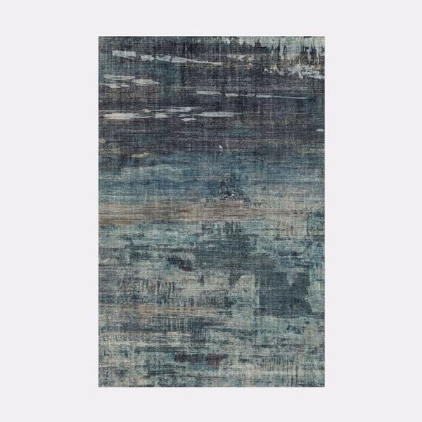 1. A West Elm Painted Strata Rug displaying a hand-loomed texture with varying shades of blue and grey, creating a visually layered appearance.