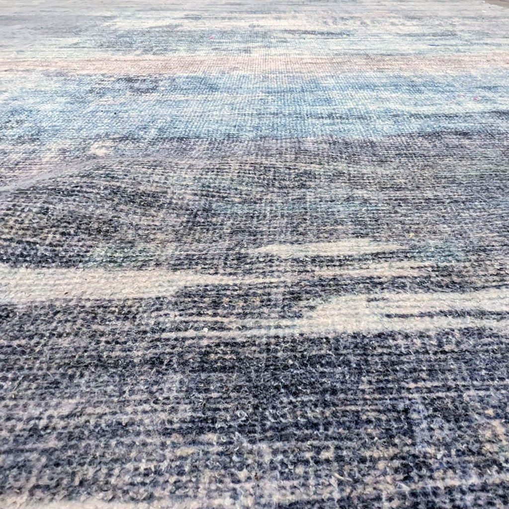 2. Close-up view of a textured West Elm Painted Strata Rug, revealing its detailed weave in hues of dark and light blues.