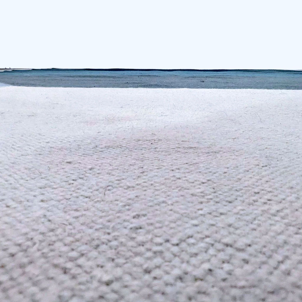 Low-angle view shows the woven wool detail and pattern of EQ3's rug.