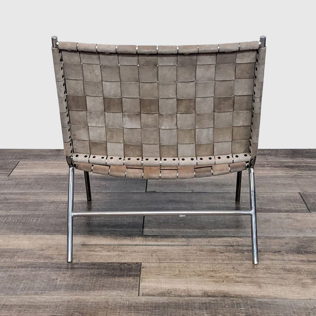 3. Rear view of a CB2 lounge chair highlighting the camel suede weave and metal frame on a herringbone wood floor.