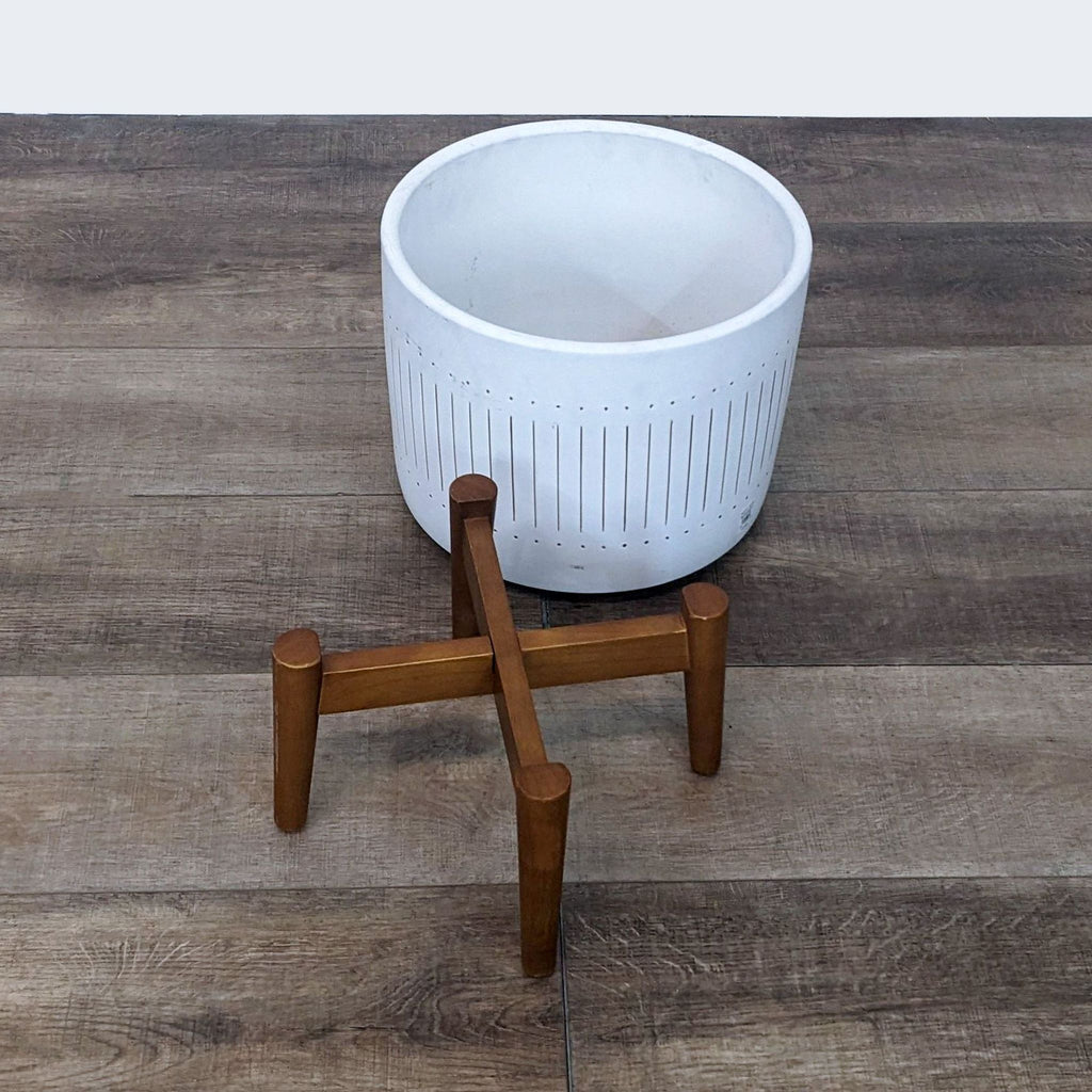 Mid-century style Turned Leg Planter by West Elm, showcasing a white ceramic bowl atop solid wood legs against a wooden floor background.