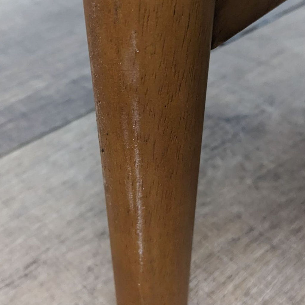 Close-up of a solid wood leg detail on the West Elm Turned Leg Planter, emphasizing its wood grain and sleek, tapered design.