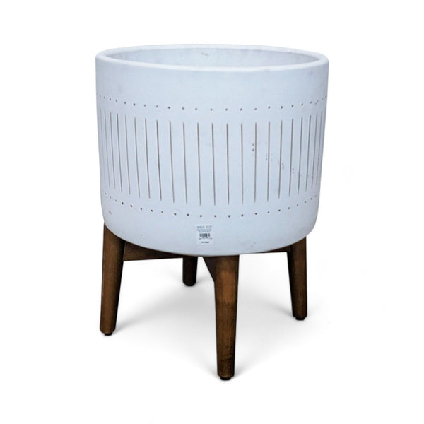West Elm Turned Leg Planter: A white glazed ceramic bowl with vertical line details, elevated on three tapered wooden legs.