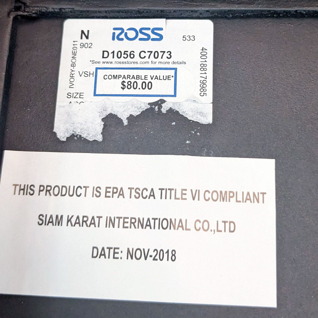 2. "Close-up of the Ross tag and compliance label on the metal base of a Reperch console table."