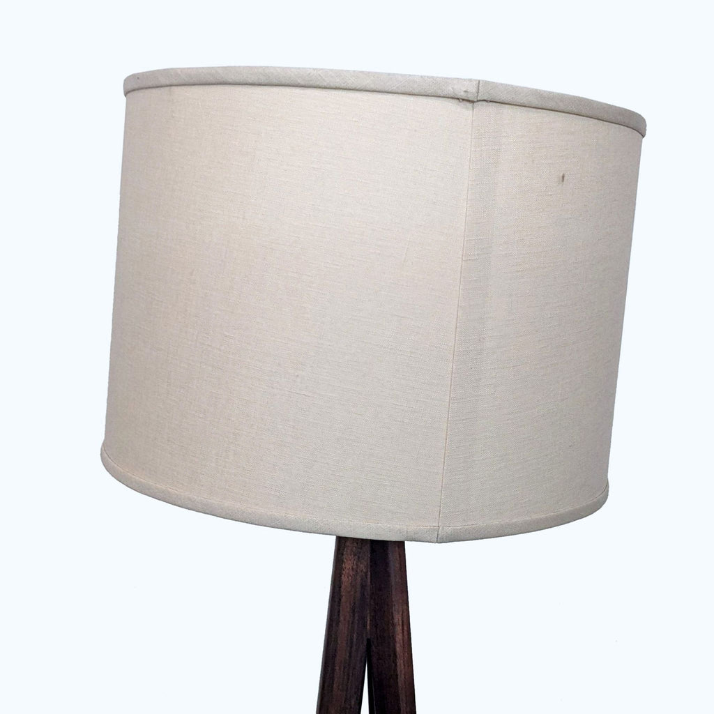 Detail of Reperch lamp's beige drum shade on a wooden stand.  