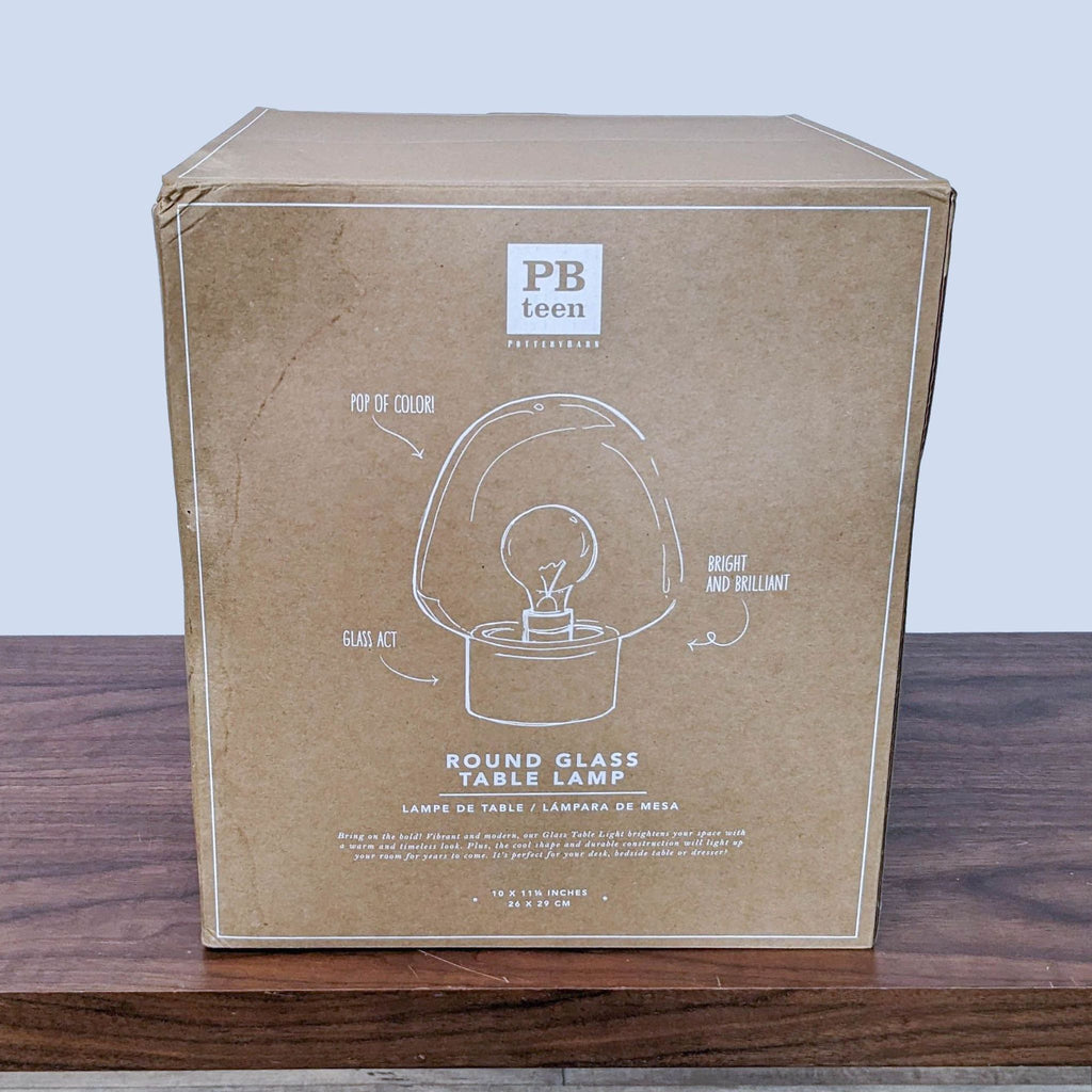 1. Pottery Barn Teen round glass table lamp packaging with product outline and branding on a wooden surface.