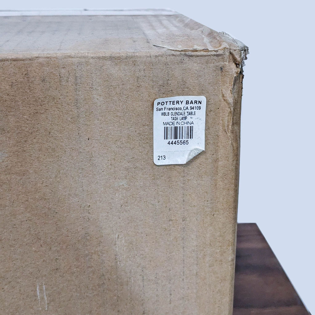 3. "Brown cardboard box with a Pottery Barn label indicating original packaging for an industrial table task lamp."