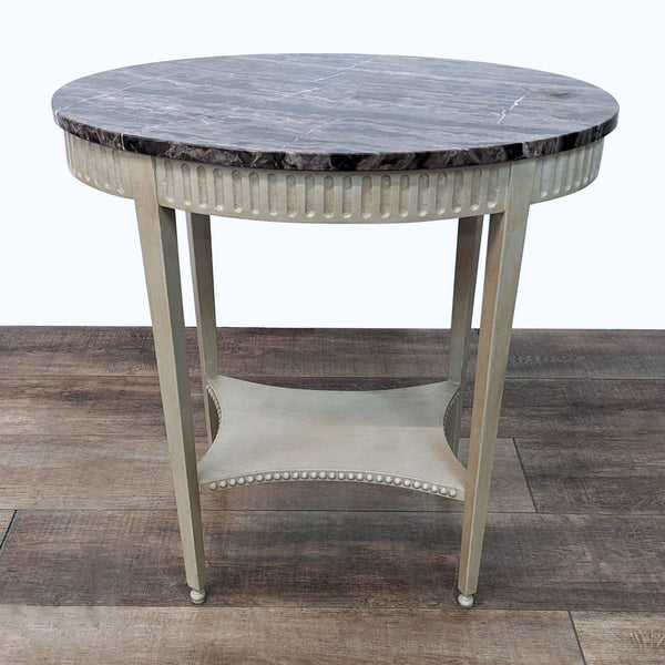 Reperch round end table with a marble top and fluted wood legs on a hardwood floor. 