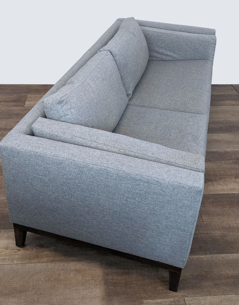 2. Side view of a heather gray Sofa Creations 3-seat upholstered couch with a cozy fabric and dark wooden legs.