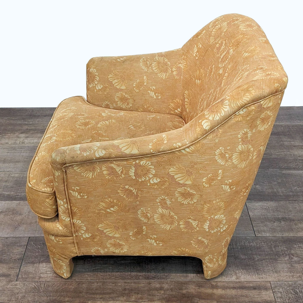 2. "Side view of a vintage-style Marisol lounge chair by Urban Outfitters with yellow flower-patterned fabric, on a wood floor."