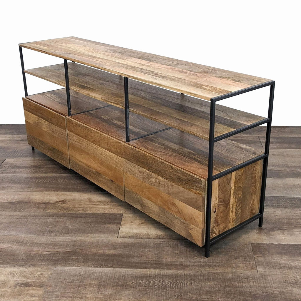 Angled view of a West Elm solid mango wood entertainment center with steel supports.