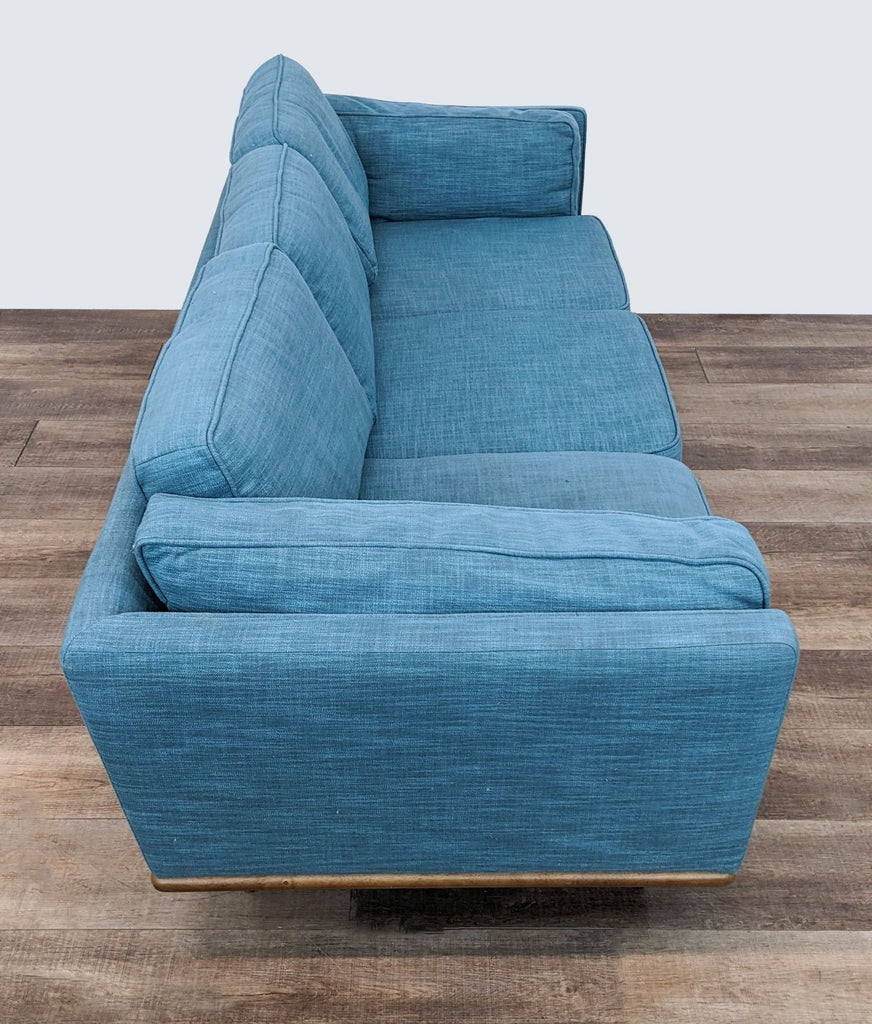 Blue textured linen 3-seat Reperch couch with wooden base, angled top view.