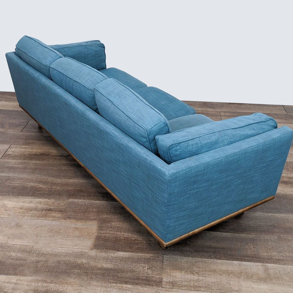 Three-seater mid-century Reperch sofa in blue fabric, angled side view on wood floor.