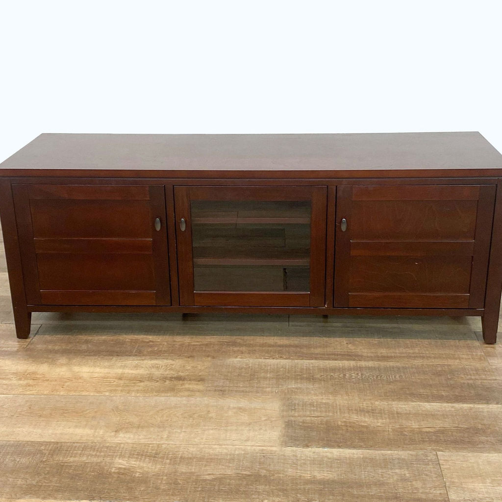 Dark brown Crate & Barrel entertainment unit with central glass cabinet and side drawers, on wooden floor.