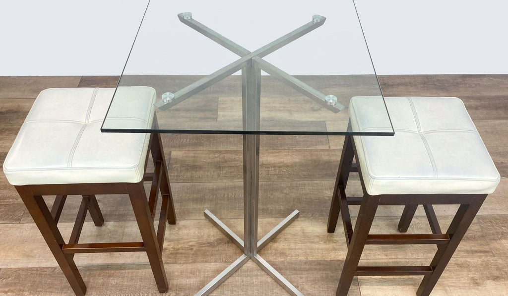 2. Overhead view of Reperch dining set showing the square glass tabletop, metallic legs, and cushioned stools.