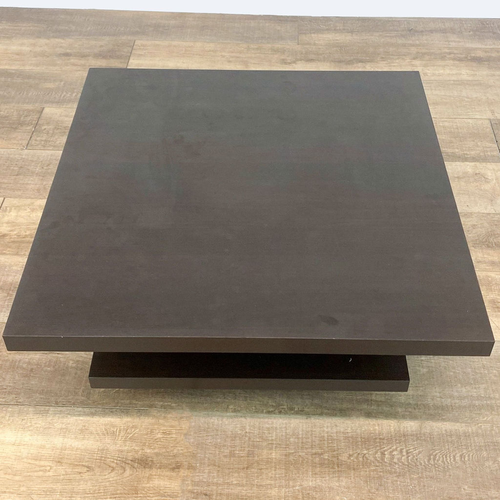 Espresso-colored Reperch square coffee table with under-tier, on a wood-textured floor in a well-lit room.