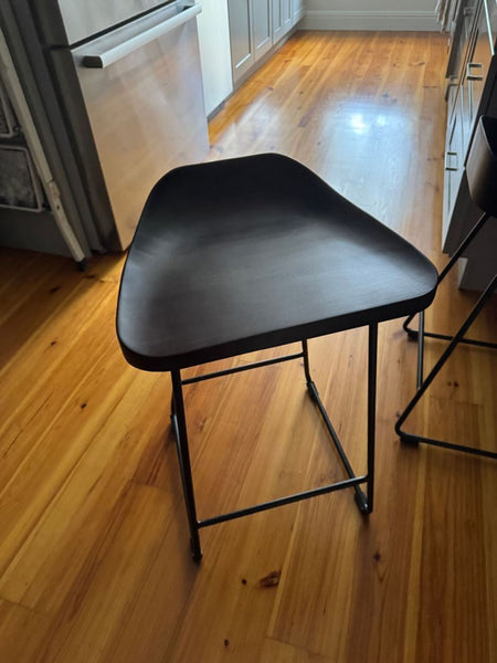 1. Modern Pottery Barn stool with a dark contoured seat and sleek metal base, shown in a bright kitchen.