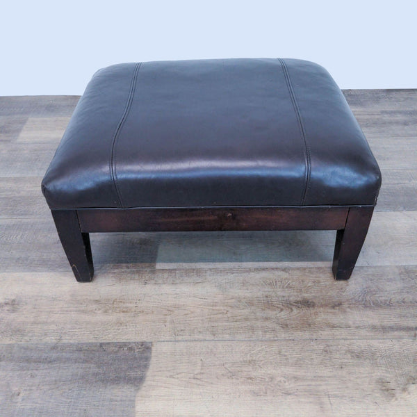 1. "Brown leather ottoman by Room And Board McCreary Modern, featuring a dark wooden frame, 29W x 26D x 15H dimensions."