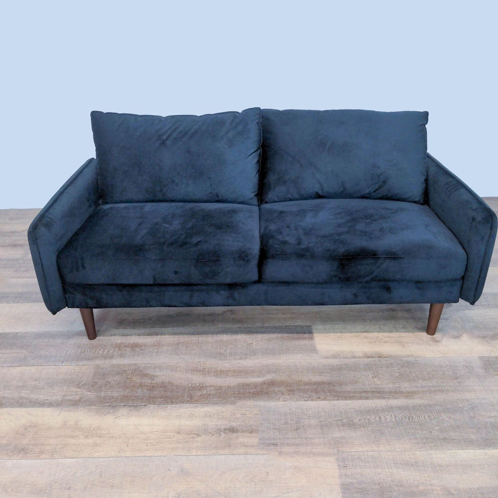 Modern loveseat with velvet upholstery and tapered wood legs.