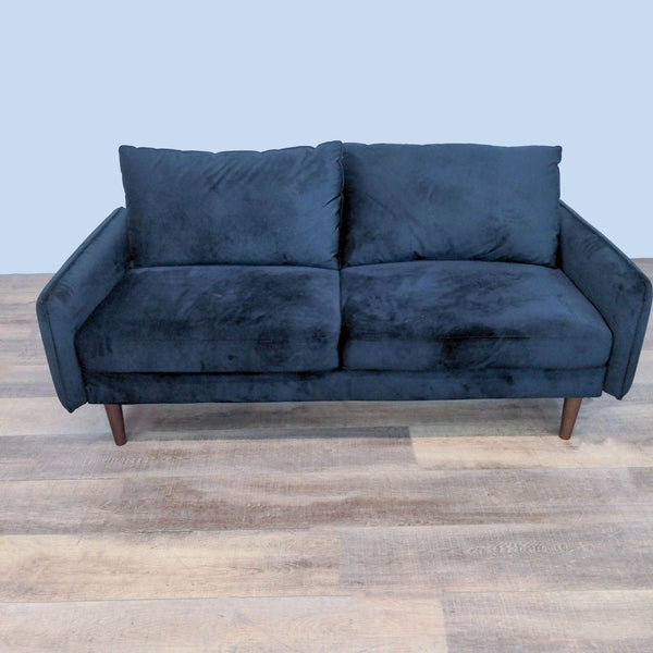 Modern loveseat with velvet upholstery and tapered wood legs.