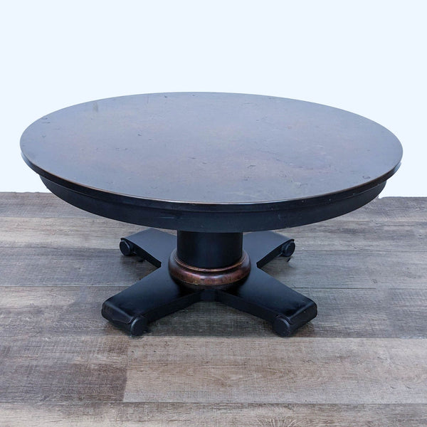 1. Round Crate & Barrel coffee table with a copper top and single pedestal base on a wooden floor.