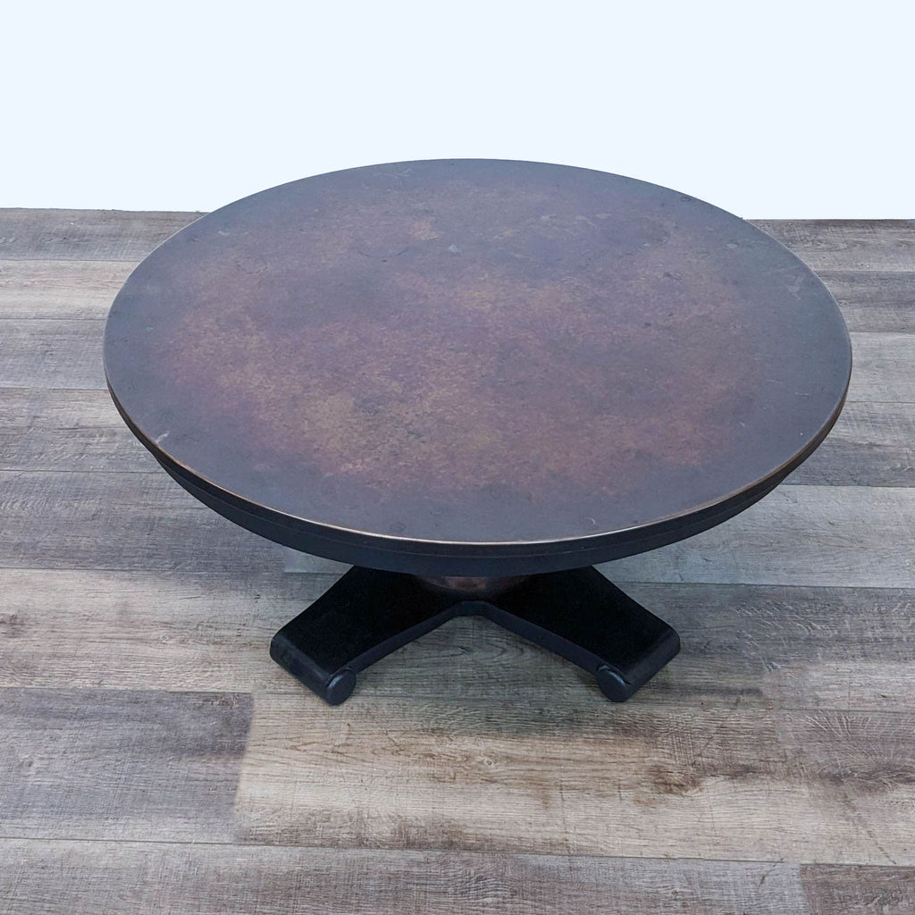 3. A Crate & Barrel coffee table with a unique round copper top and a sturdy black pedestal base.