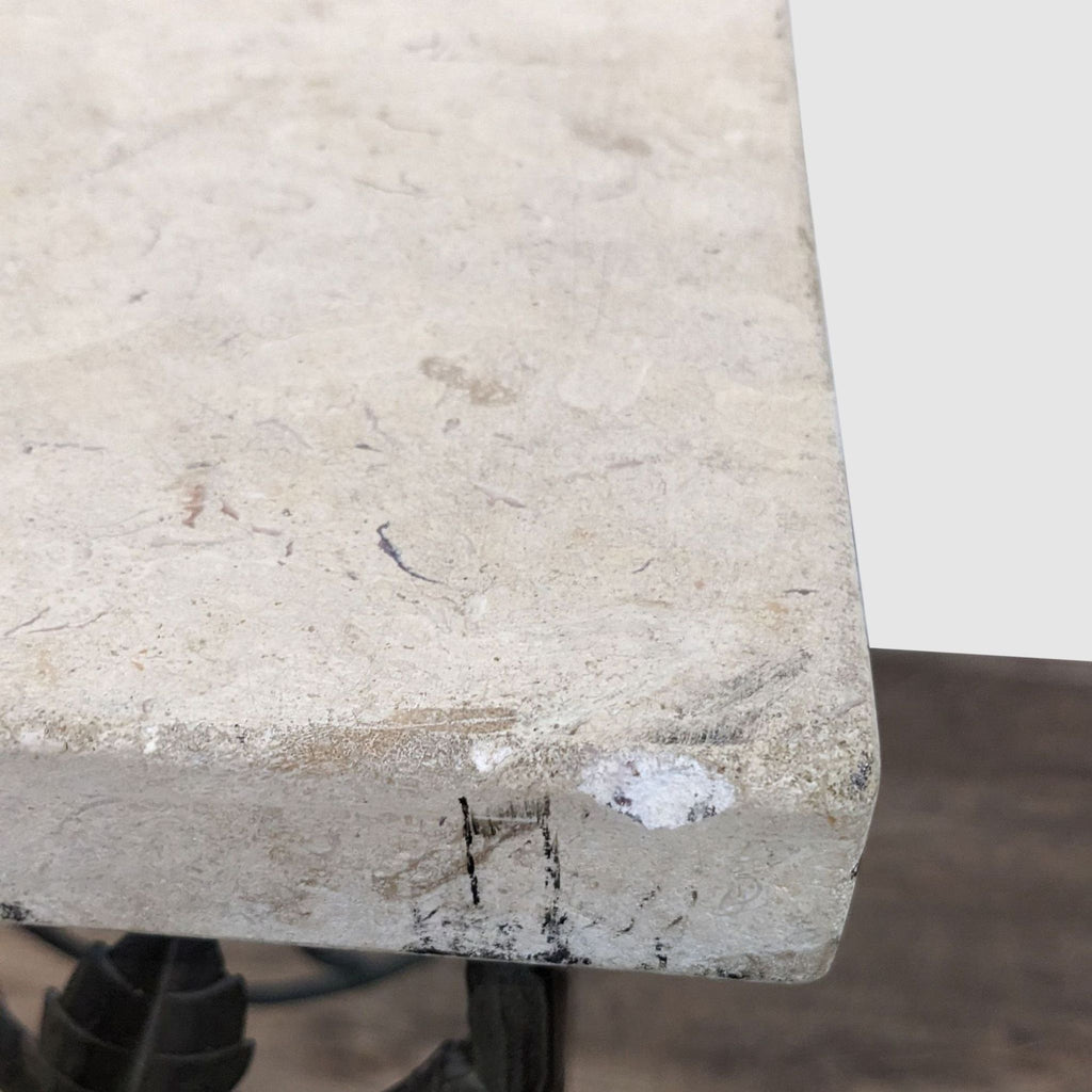 Close-up of a Reperch table corner, highlighting the marble surface and detailed wrought iron leaf patterns.