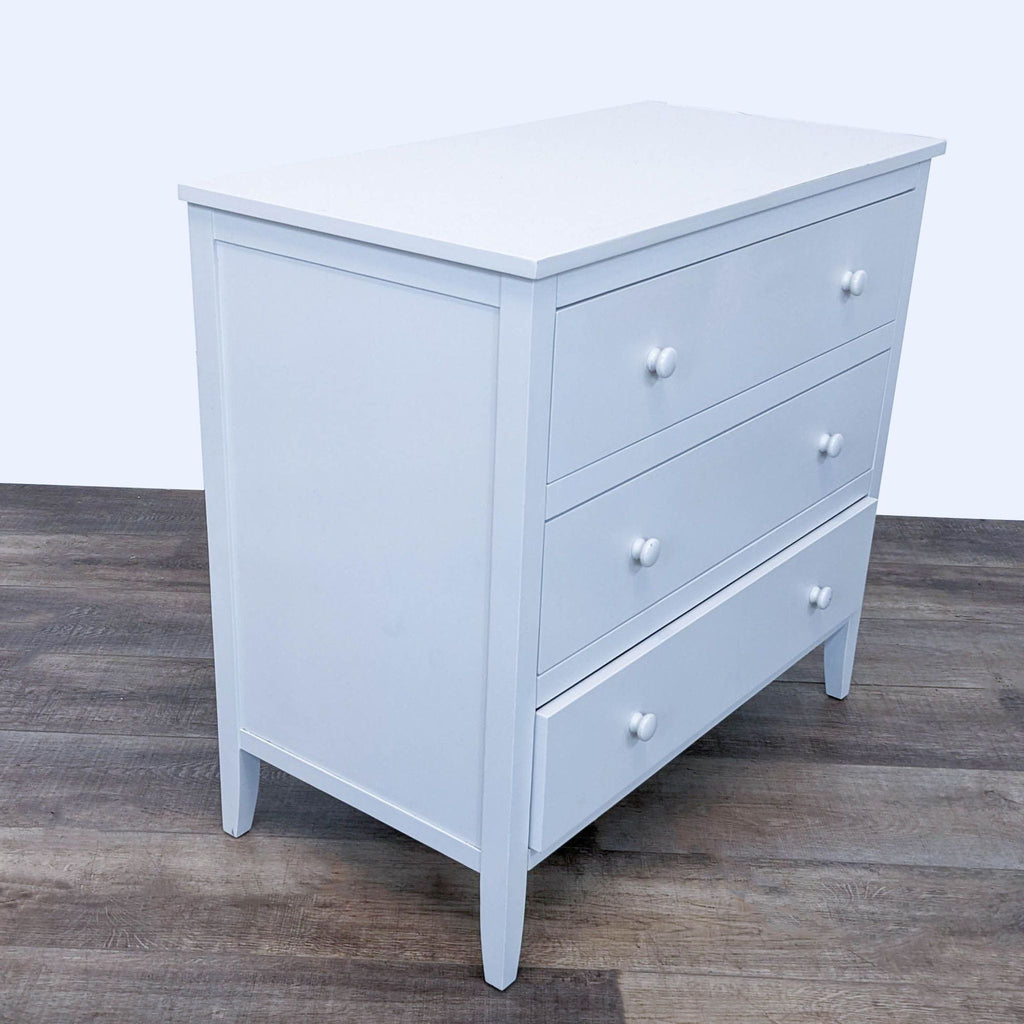 2. Angled view of a white, rubber wood and veneers Emerson dresser by Pottery Barn Kids with three drawers and simple knobs.