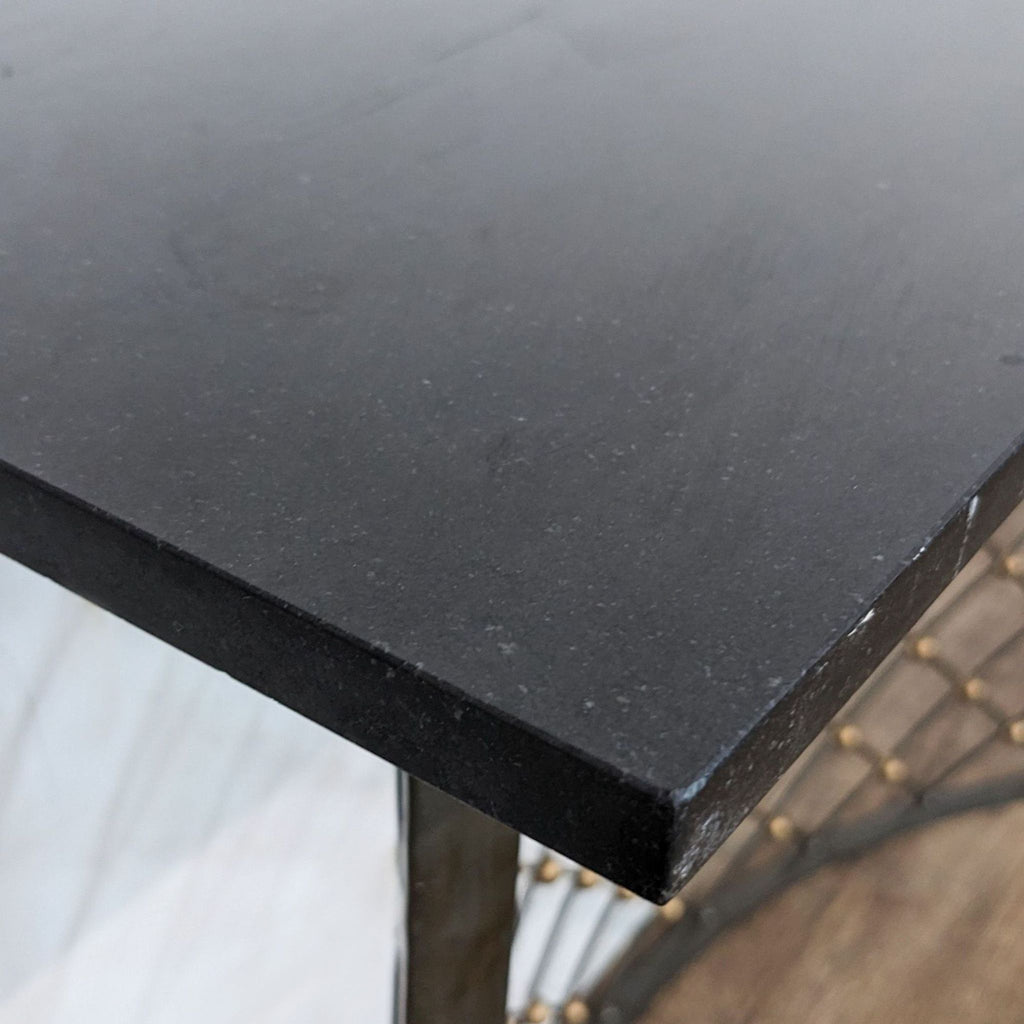 3. Close-up on the black tabletop texture of a Reperch console table with a glimpse of the wrought iron lattice base.
