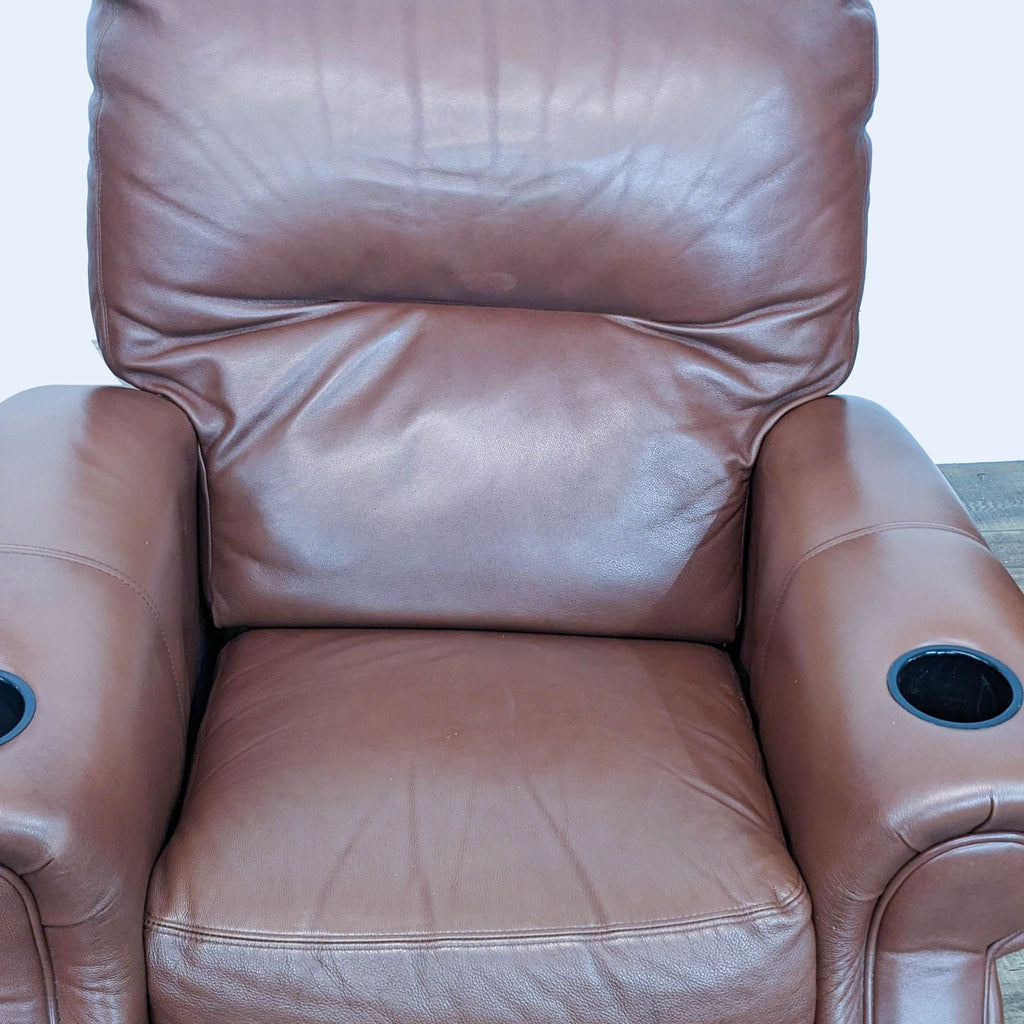 3. Close-up of a single Reperch reclining seat, highlighting the plush leather upholstery and the cup holder on the armrest.
