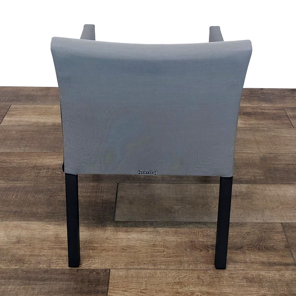 Rear view of Ventana dining chair showcasing grey fabric and brand label on backrest.