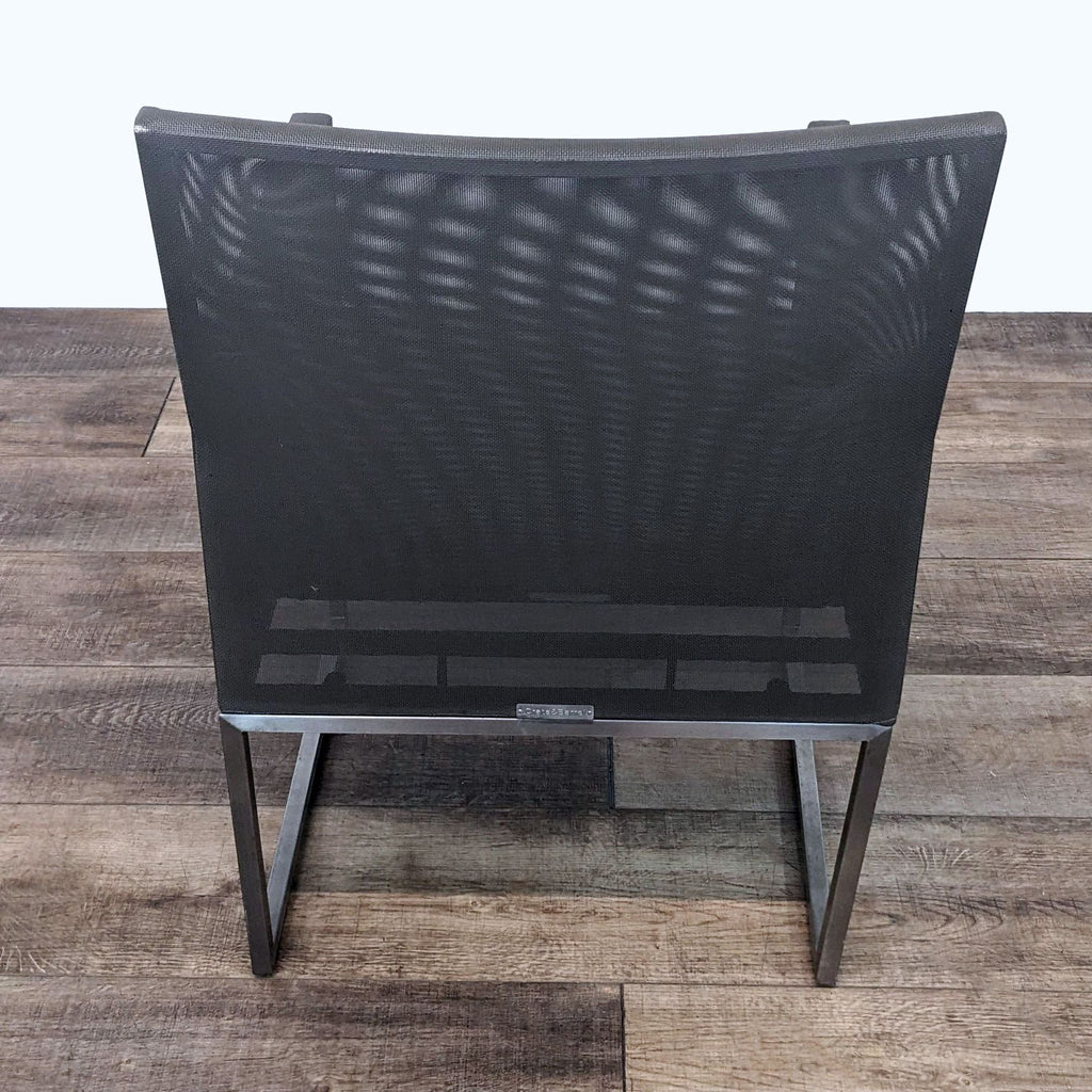Back view of a Crate & Barrel outdoor dining armchair showcasing sturdy aluminum frame and mesh backrest.