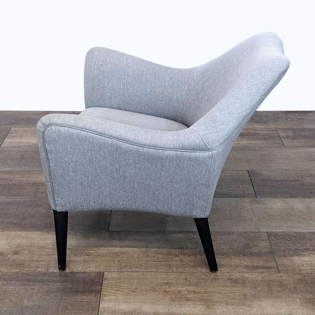 Angled view of a Reperch grey upholstered lounge chair with a comfortable deep seat and sturdy legs.