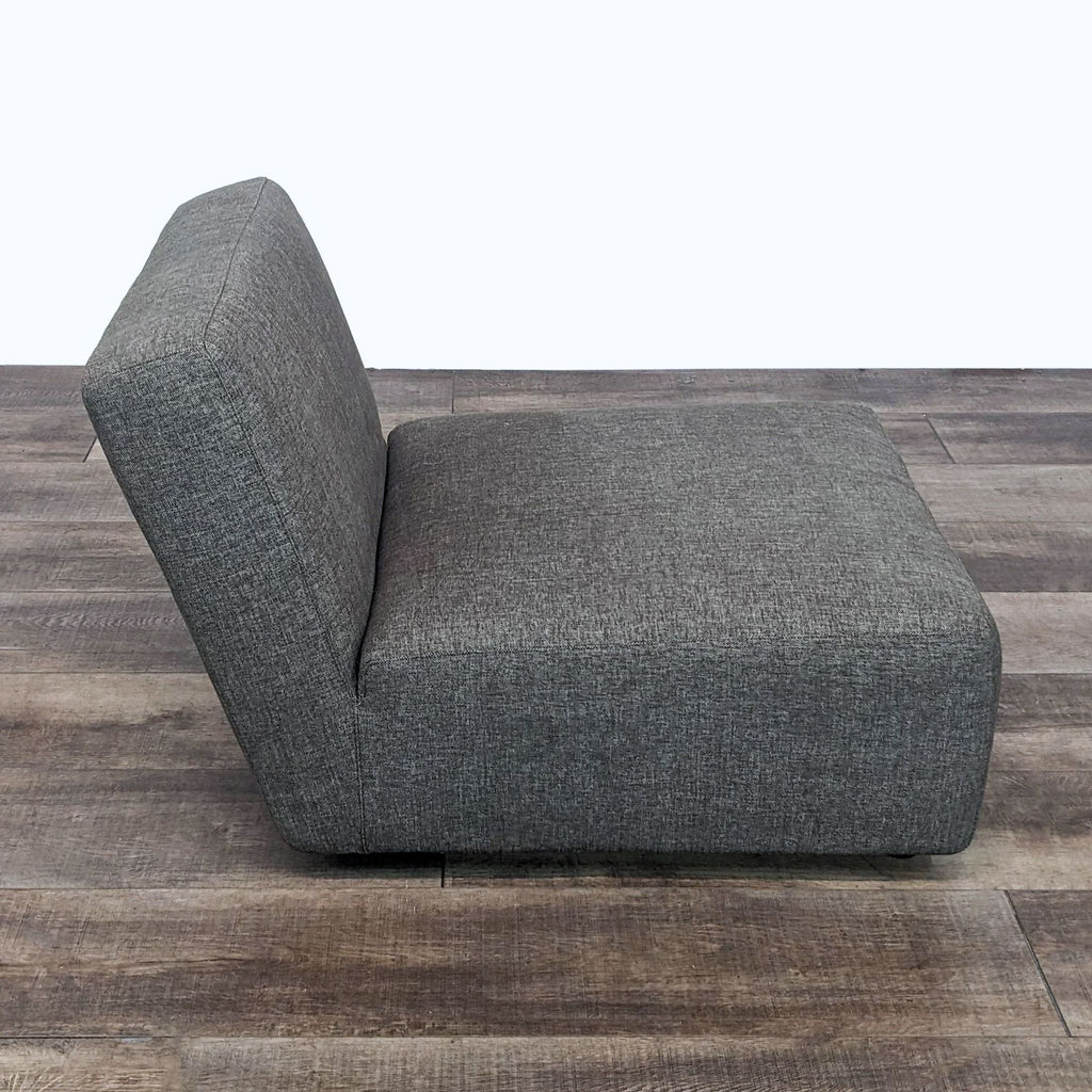 2. Side view of a contemporary Reperch lounge slipper chair in dark gray with a sleek profile on a wooden floor.