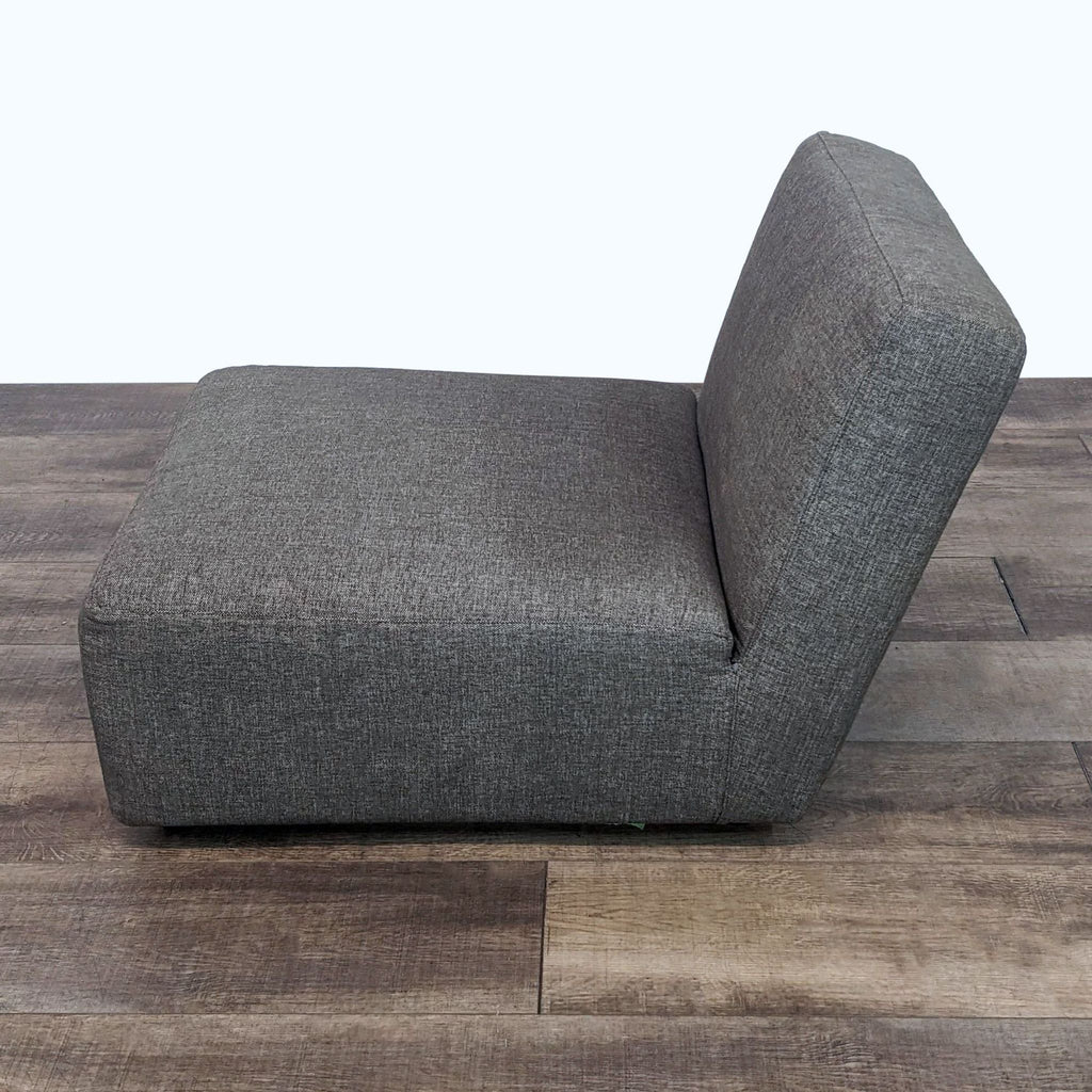 3. Reperch's modern slipper chair featuring dark gray textured fabric and wood feet, displayed in a room setting with wood flooring.