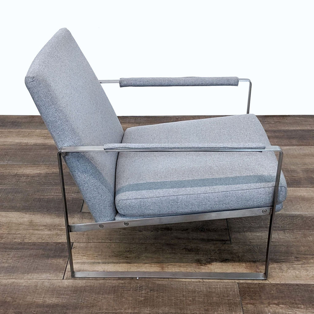 2. Side angle view of a Reperch grey upholstered lounge chair with padded arms and a sturdy metal frame, on a wooden floor.