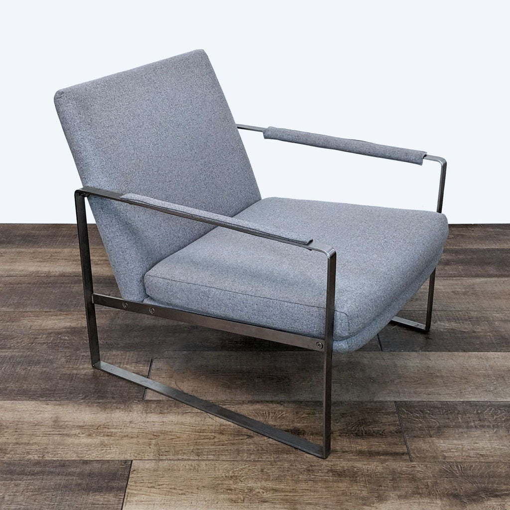 3. Three-quarter perspective of a grey fabric Reperch armchair showcasing the clean lines and modern design on a wood-patterned floor.