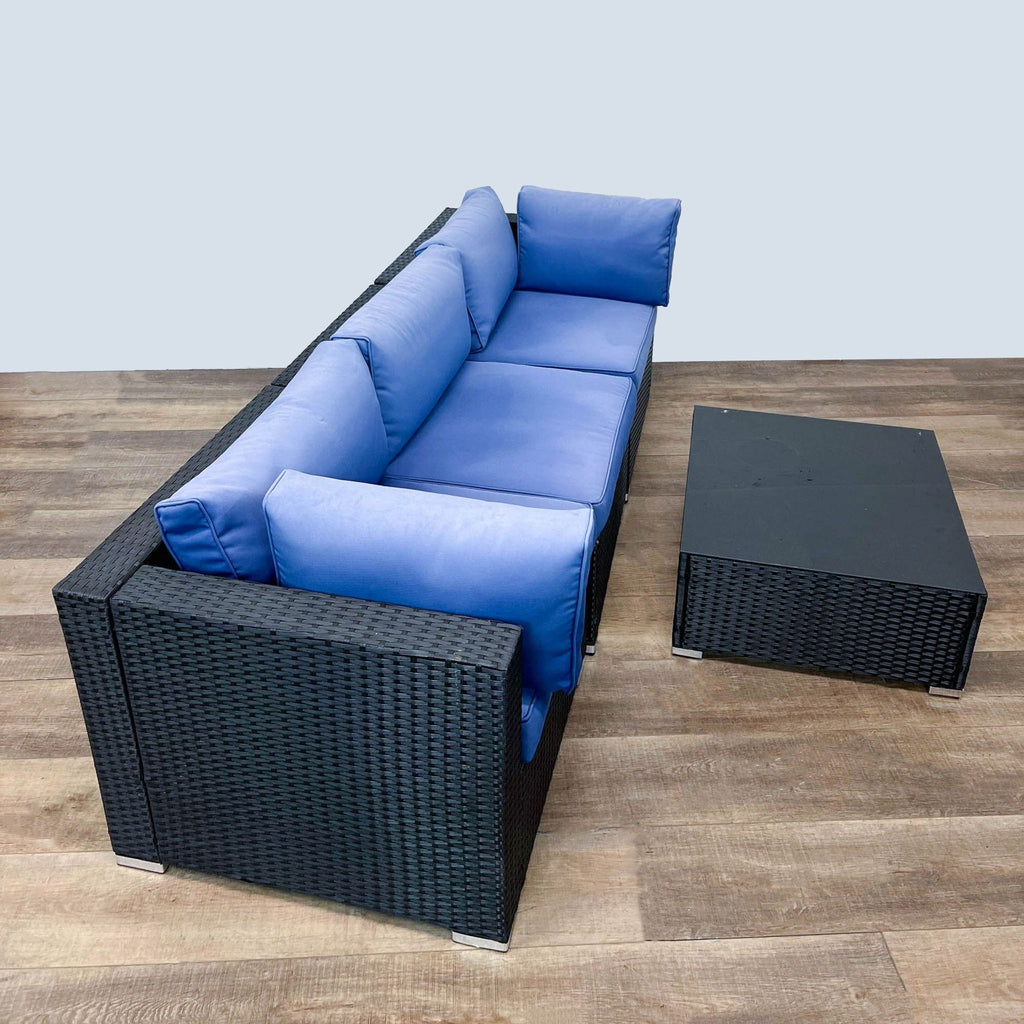 Reperch rattan L-shaped outdoor sofa with matching coffee table and vibrant blue cushions.
