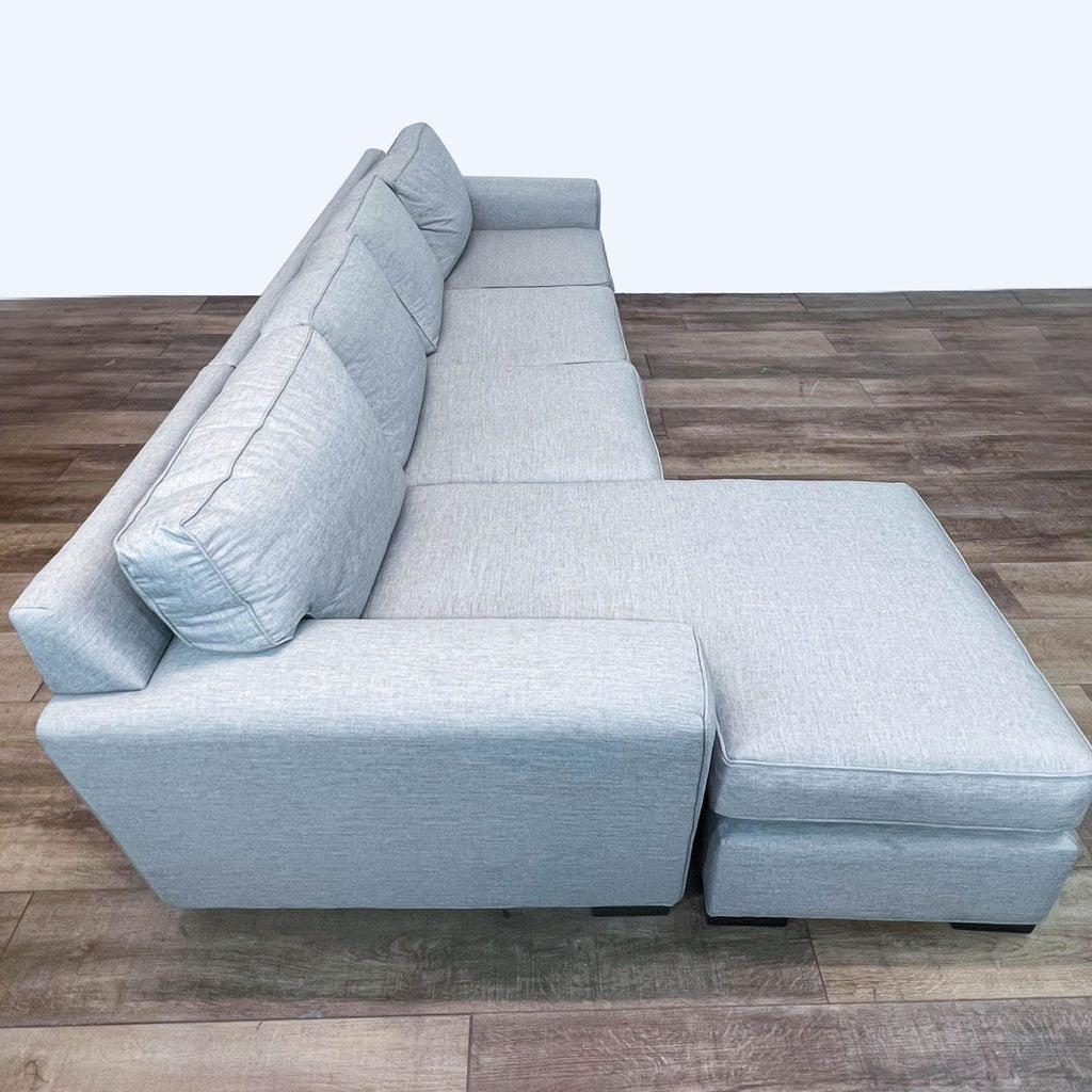 Light gray Stanton sectional sofa view from the side, showing detachable chaise and cushioned armrest, on wood flooring.