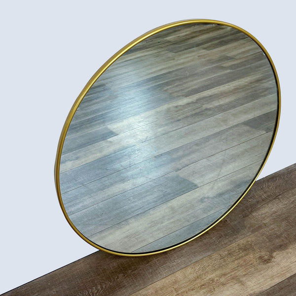 Williams-Sonoma round mirror with a brass-toned frame on wood floor.
