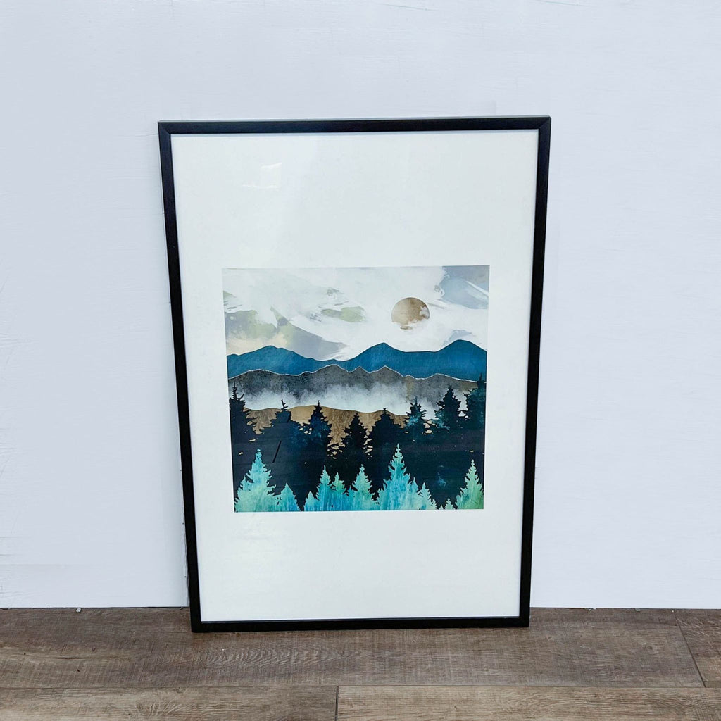 1. Framed SpaceFrog painting depicting misty mountains, full moon, and a dark forest against a pale sky placed against a white wall.