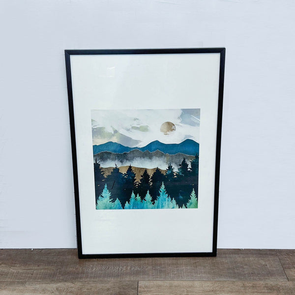 1. Framed SpaceFrog painting depicting misty mountains, full moon, and a dark forest against a pale sky placed against a white wall.