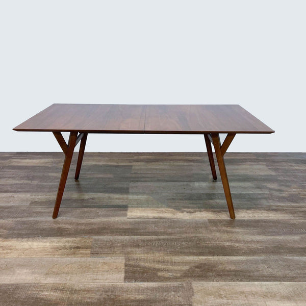 Mid-century West Elm dining table with angled legs and warm wood finish.