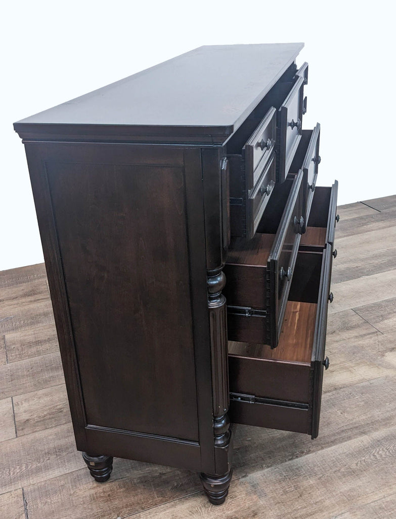 Side view of Ashley Signature 7-drawer dresser showing open drawers and intricate details in a sophisticated dark finish.