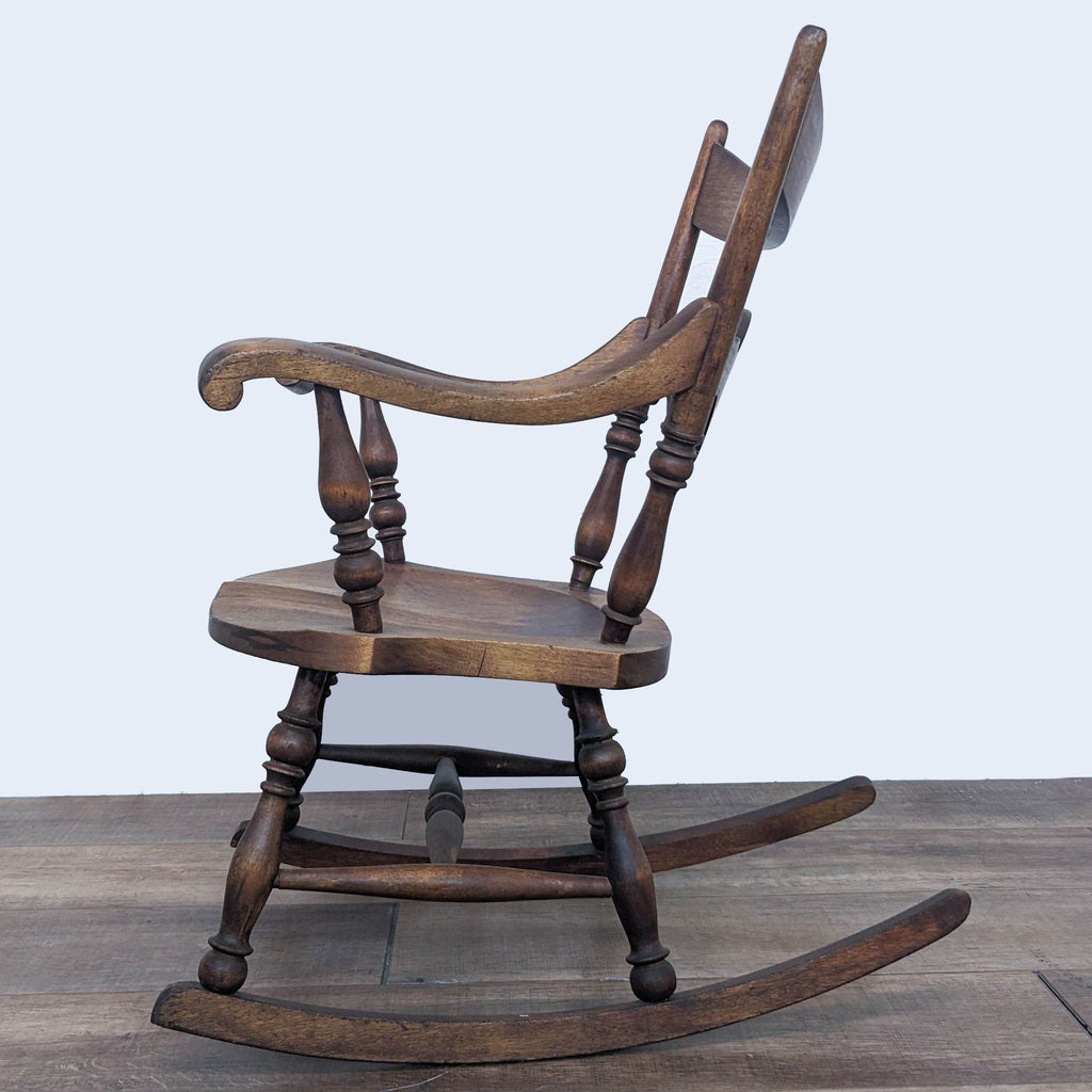Vintage Reperch solid wood rocker with turned spindles, side angle on a wooden floor.