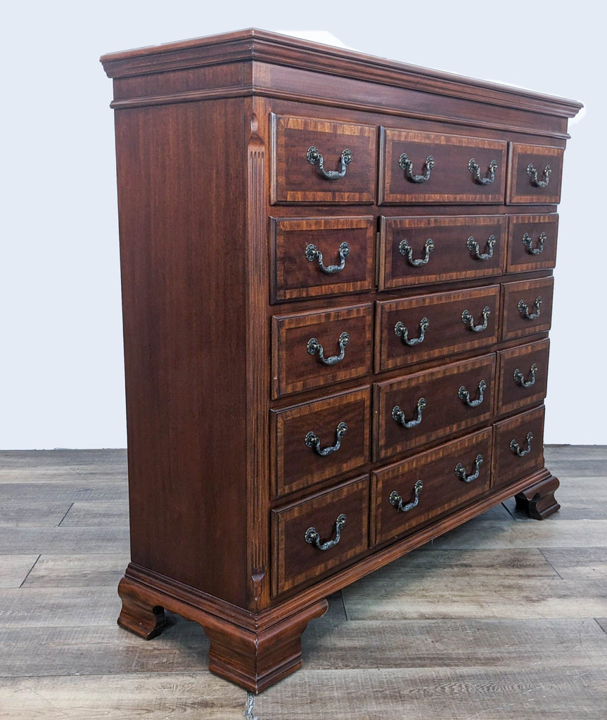 Side angle of Reperch wooden dresser with 15 drawers featuring classic drop handle pulls, on a wooden floor.