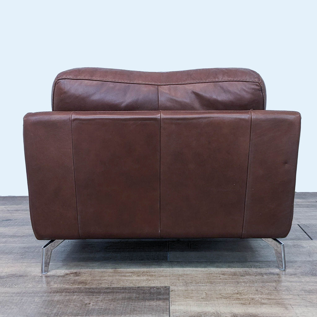 3. Rear view of Scandinavian Designs Peruna lounge chair, displaying the full leather wrap and chrome leg design on a wooden floor.