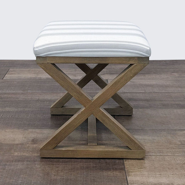 Solid wood Reperch ottoman with white striped upholstery and X-frame design on wooden floor.