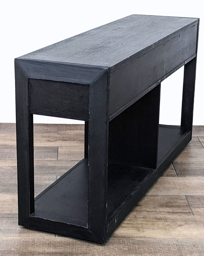 Angled view of a black side table by Living Spaces with drawers closed and an open lower shelf.